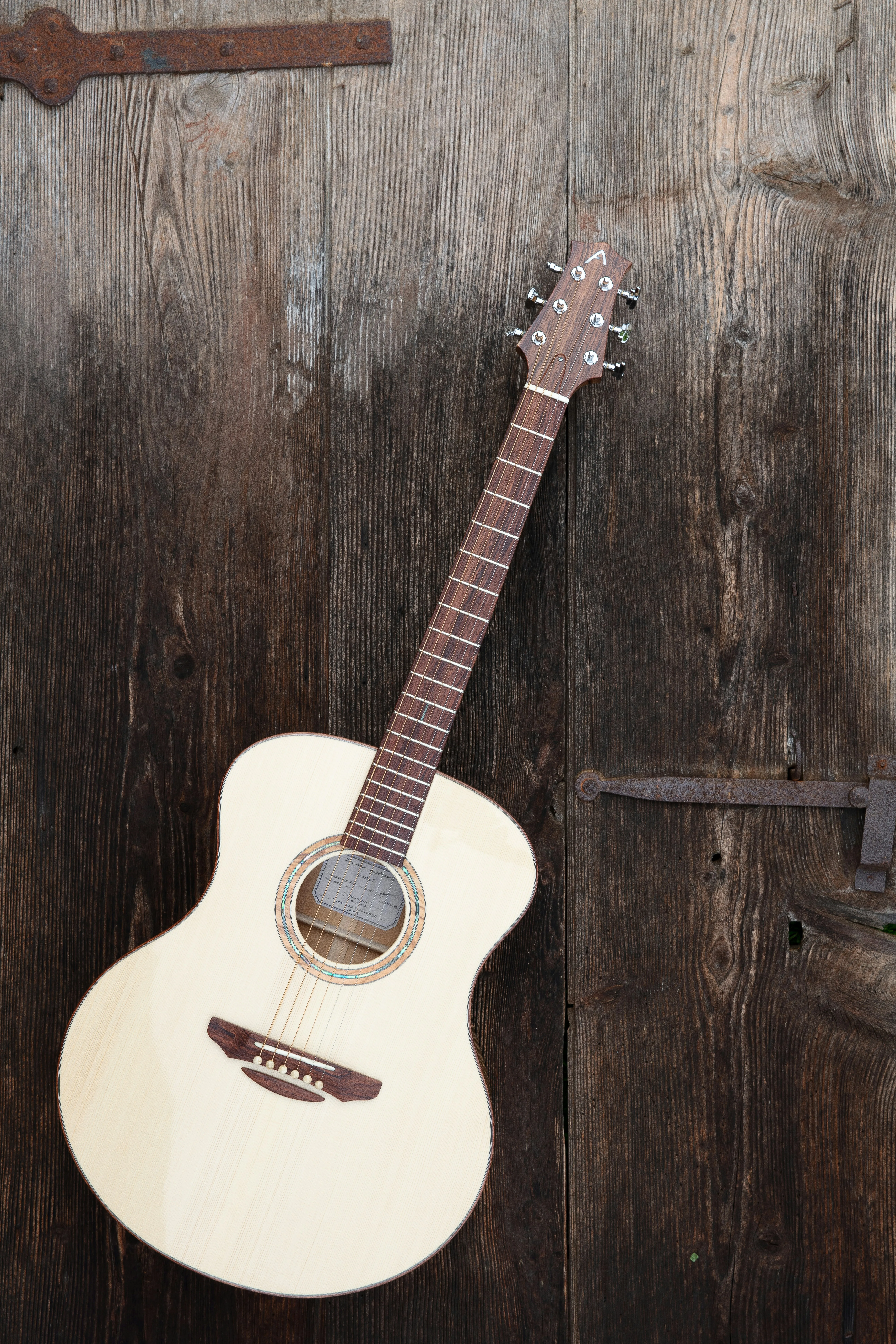 A parlor-sized acoustic guitar leaning against a rustic wooden door — compact, focused, and more useful on a worship stage than most players expect