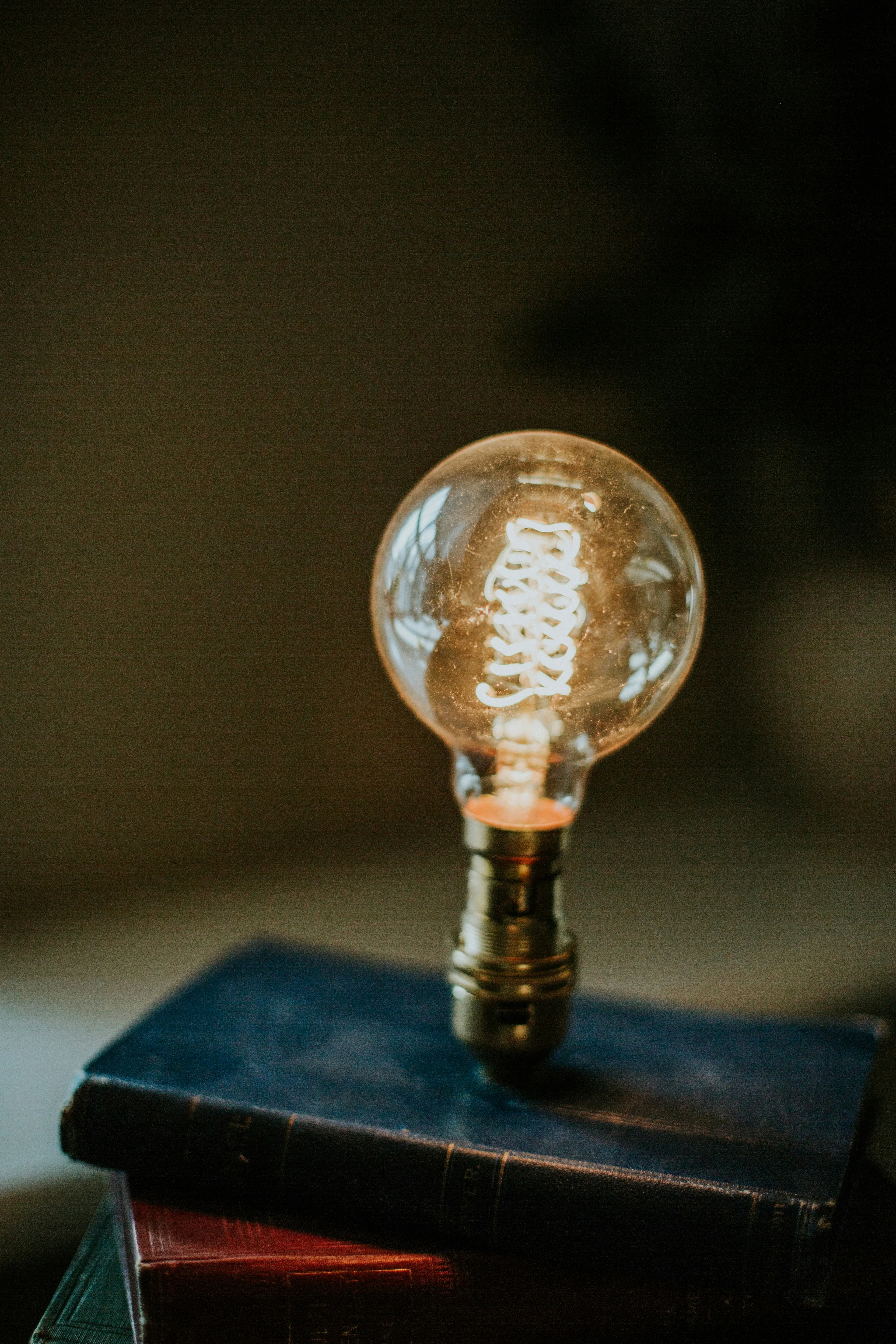 A lit lightbulb resting on a stack of old books — the kind of slow-burning realization that came well after the 30 days were over