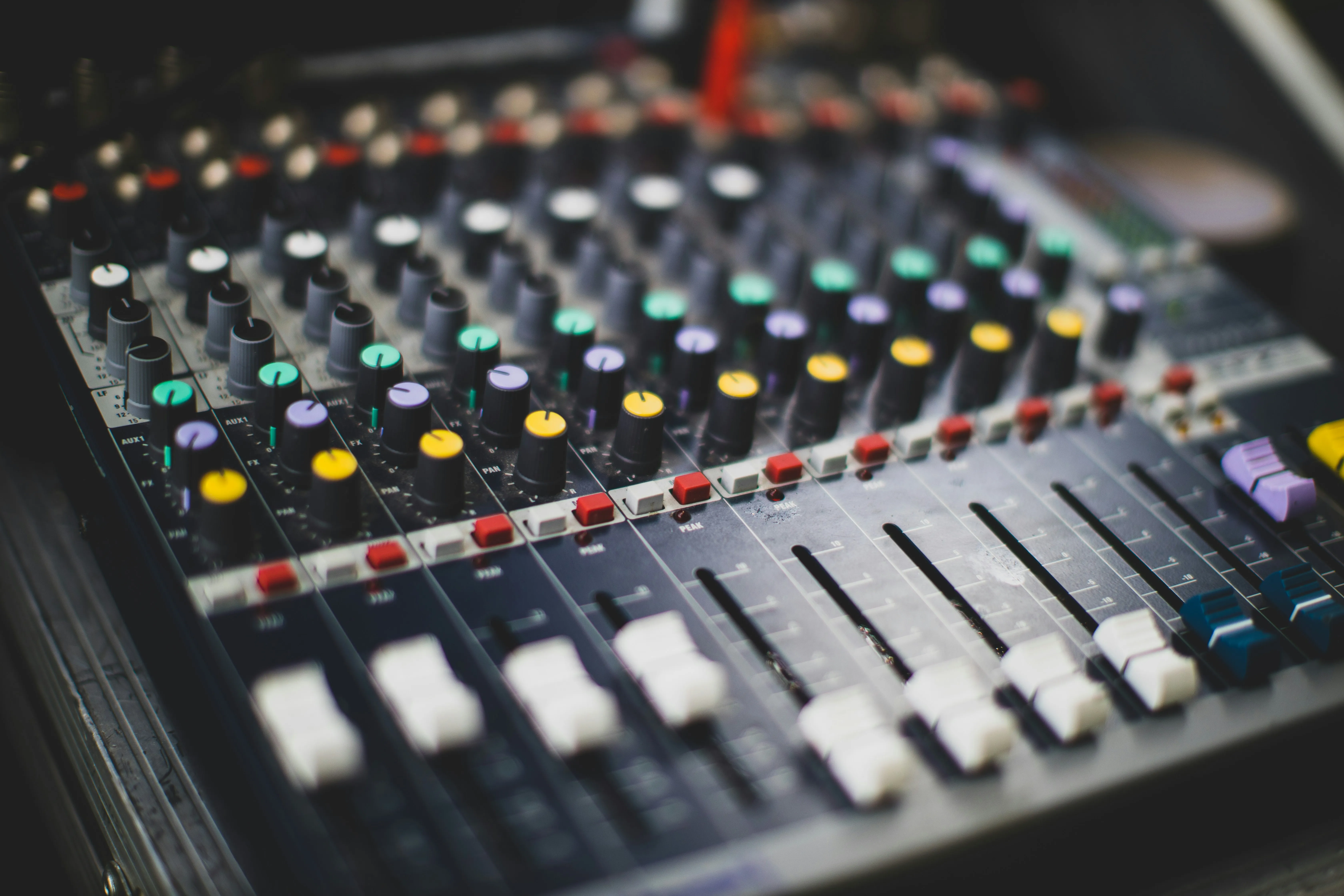 Close-up of a church mixing board with colorful knobs and faders ready for Sunday service