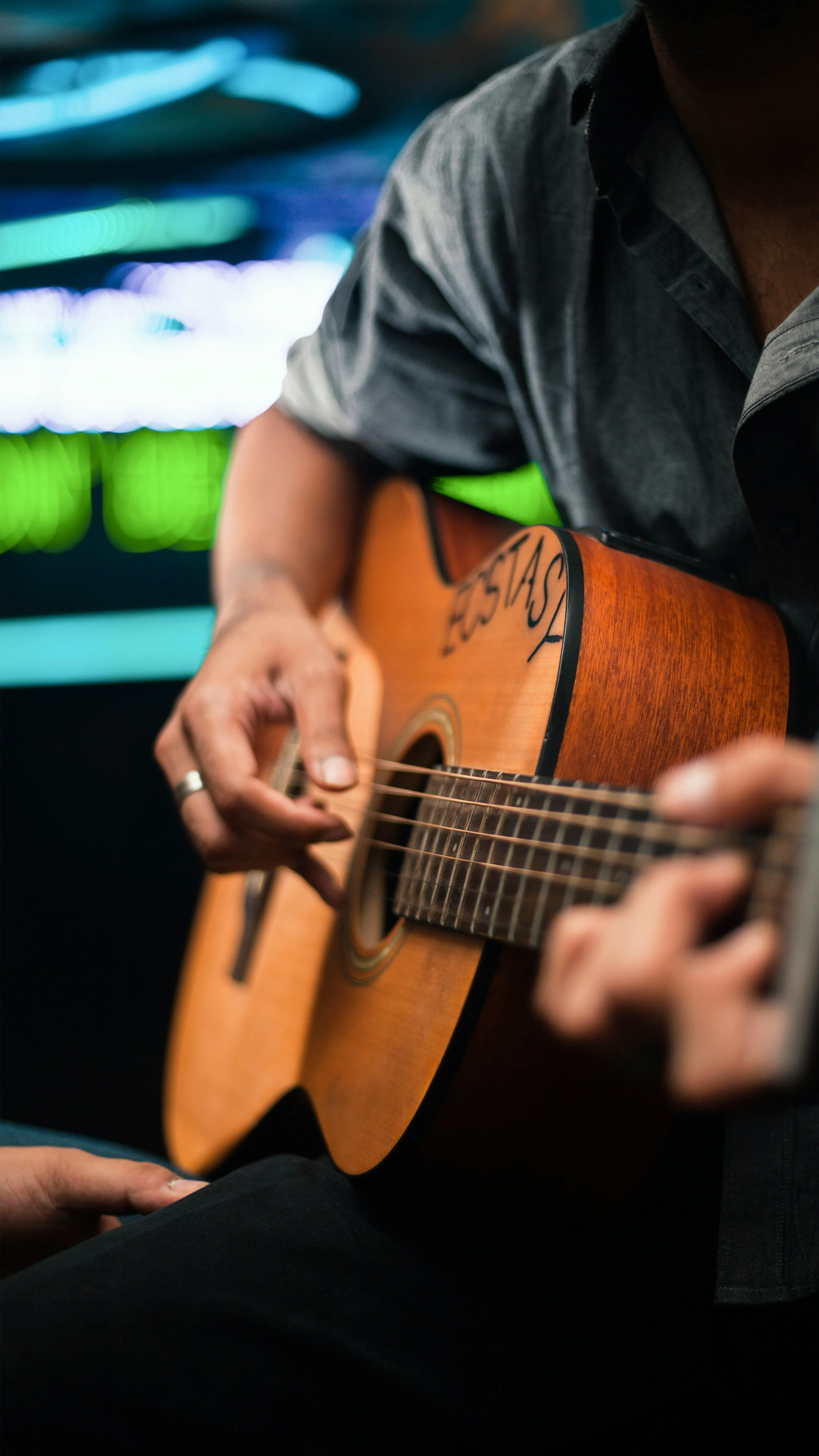 A close-up of hands forming a chord on an acoustic guitar — the barre chords that still don't fully cooperate