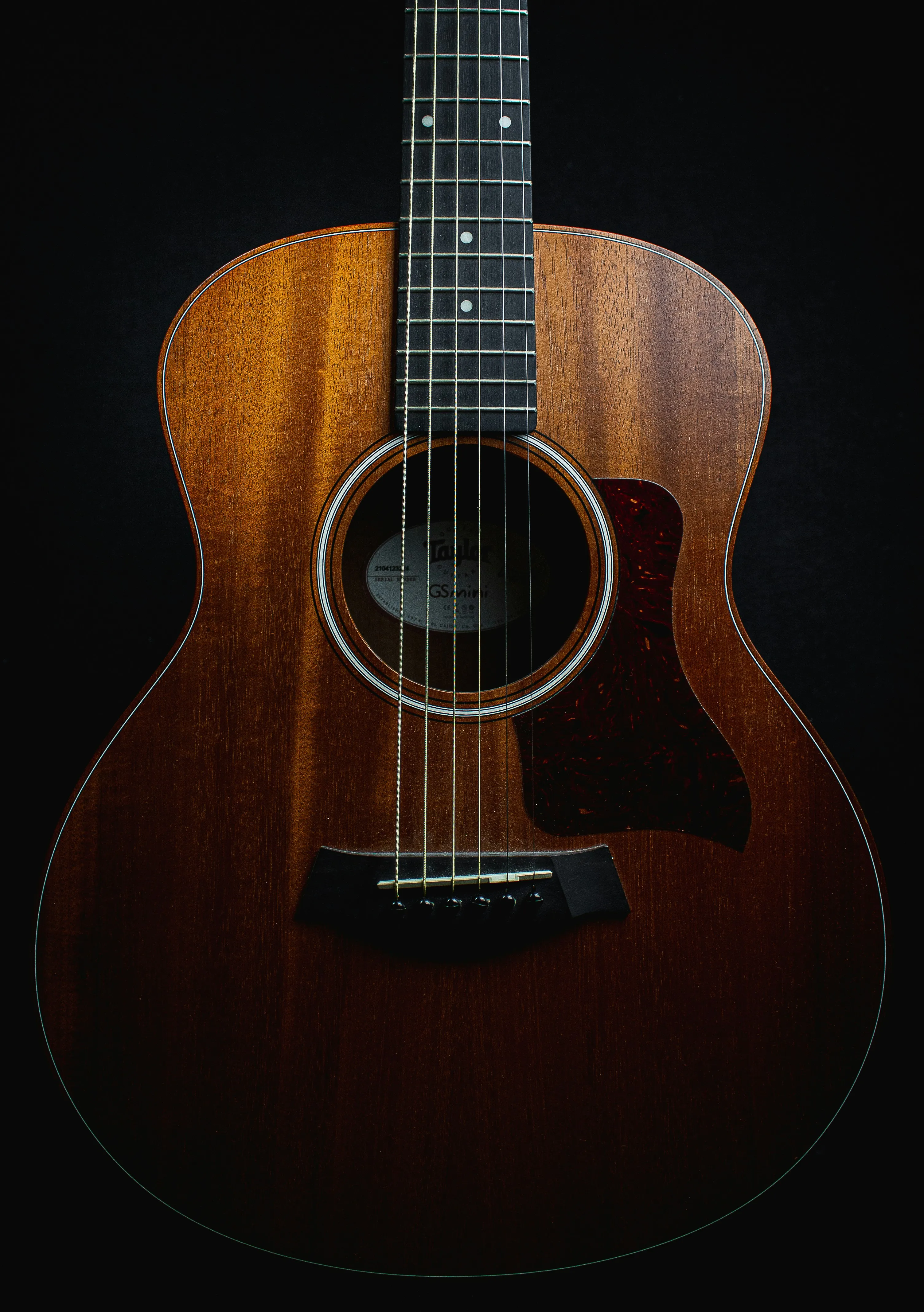 Close-up of a Taylor acoustic guitar body showing the warmth of its mahogany top and clean soundhole detail
