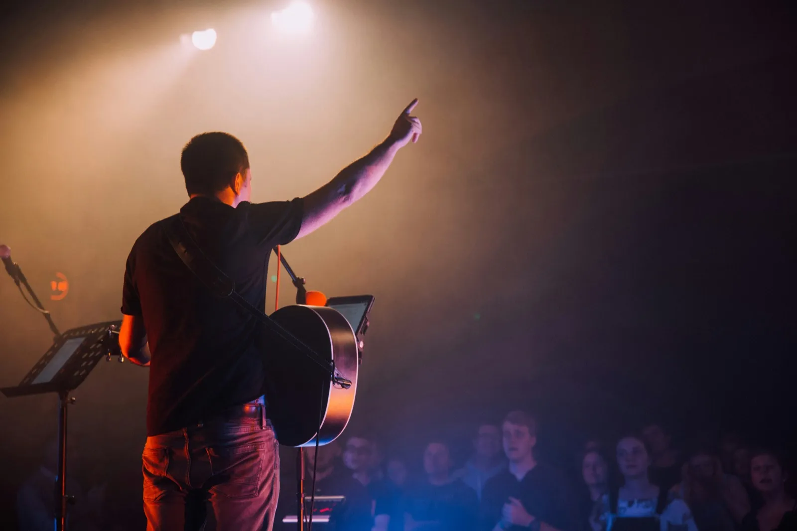 Worship guitarist pointing upward during a live church service