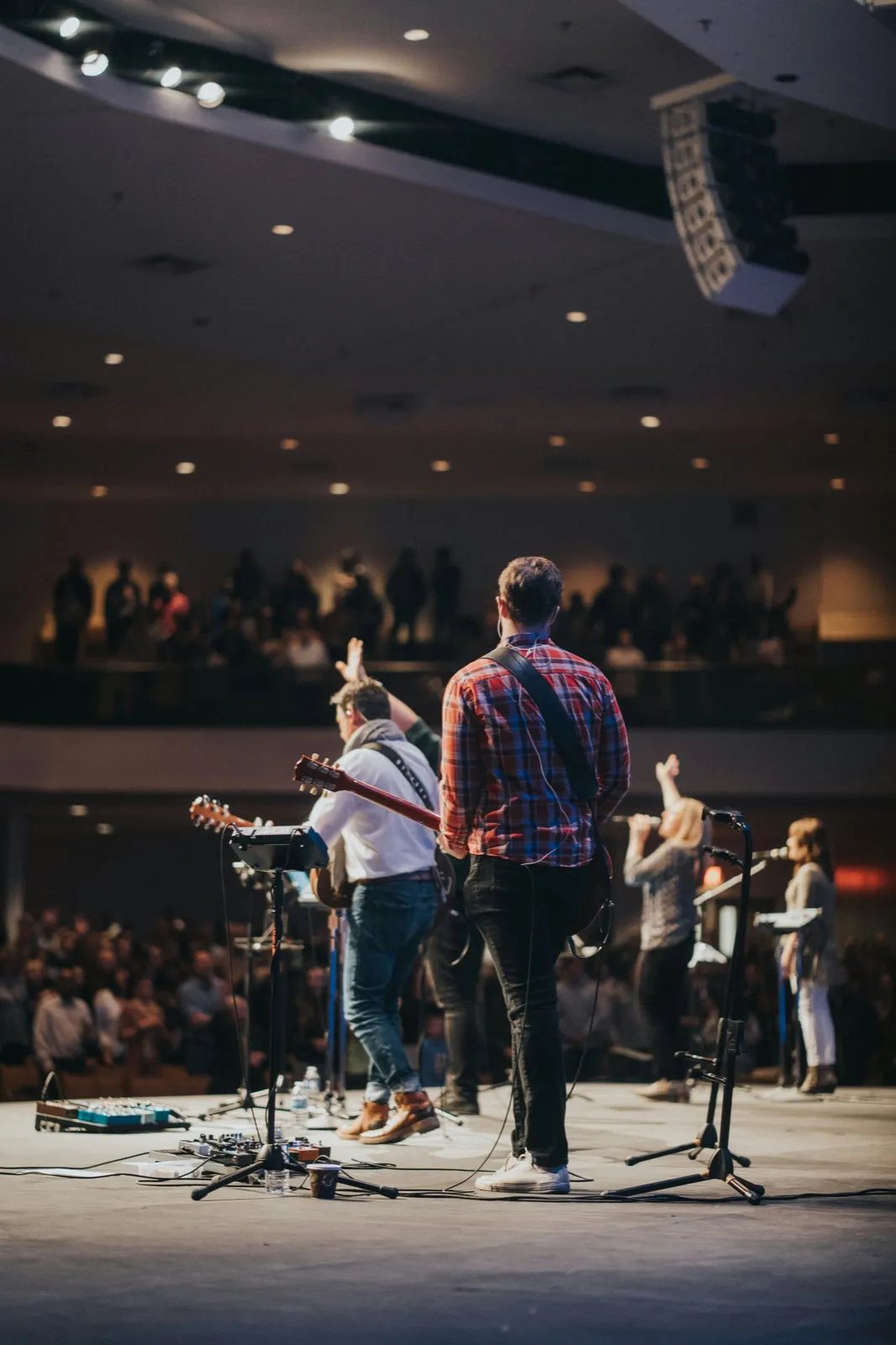 Worship leader on stage facing the congregation with guitar in hand