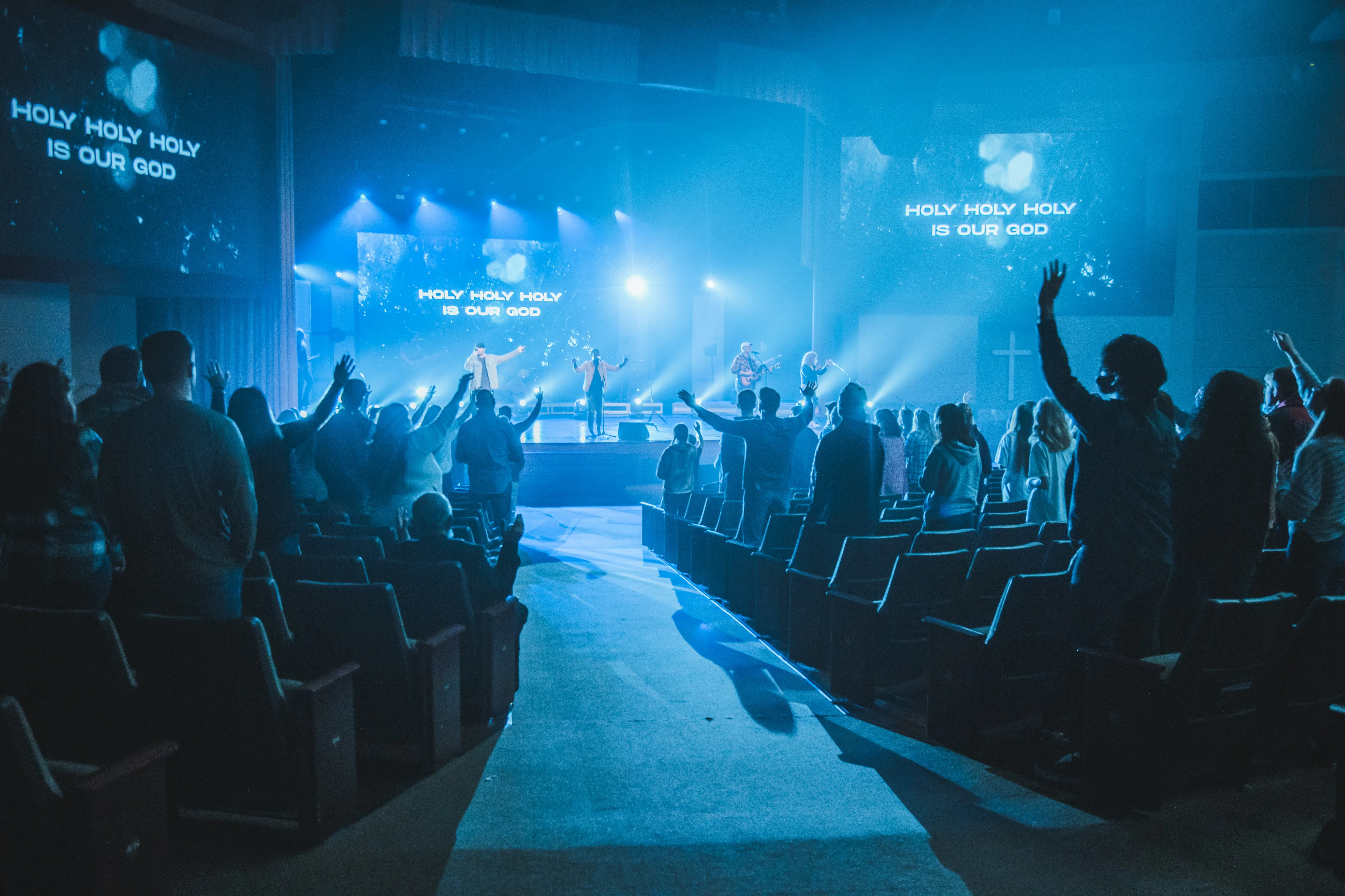 A congregation with hands raised — the response that tells you a song still works